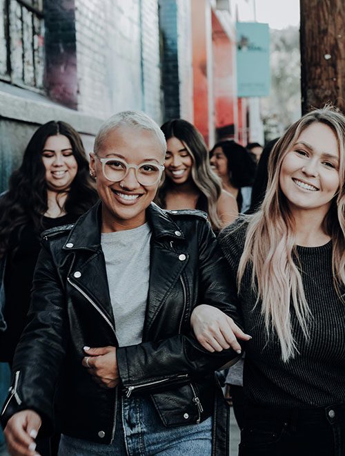 Group of smiling women walking arm in arm